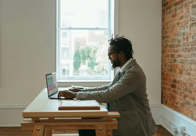 A professional working on a laptop at home with natural light, minimal distractions, and a calm environment.